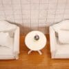 Two white chairs and a table on a wooden floor.