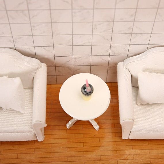 Two white chairs and a table on a wooden floor.